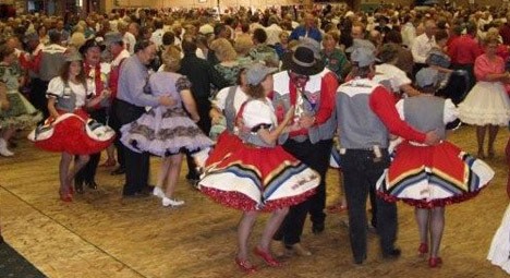 Dancers twirl at a square dancing event held in a hotel ballroom. Now