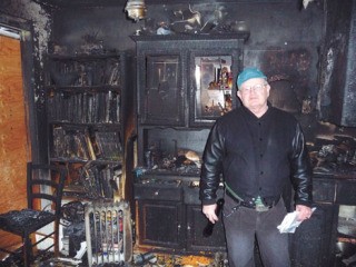 Doug Comstock stands in his blackened living room. The family is in temporary shelter in two Maury Island cottages.