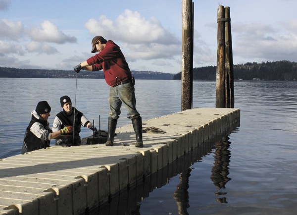 Volunteers Erin O’Reilly and Ashley Merchant and Camp Sealth employee Eric Miller work on a dock at the camp.