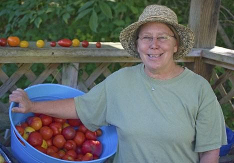 Michelle Crawford holds a large basket of tomatoes grown at Pacific Potager.