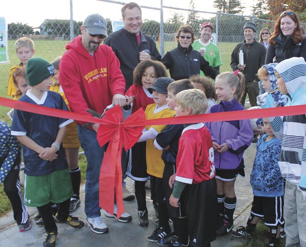 Vashon Park District Commissioner Joe Wald and some kids cut the ribbon at the park district’s partially completed field complex.