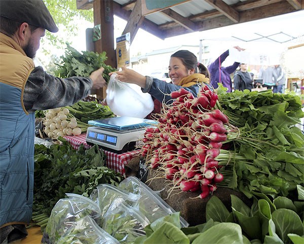 Jen Keller of Pacific Crest Farm sells a customer a bunch of kale at Saturday’s Farmers Market. Soon