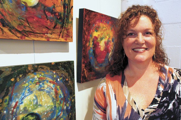 Lisa Hurst stands in front of her colorful abstract art at Ignition Studios.