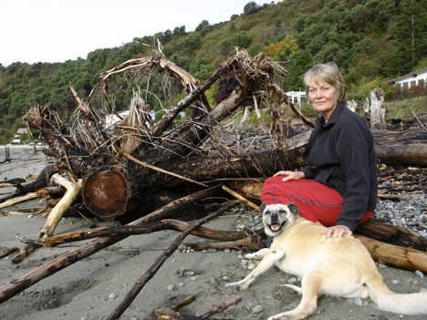Annie Strandberg with her dog Lexie sit next to one of the sawed-off root masses near her home at Gold Beach.