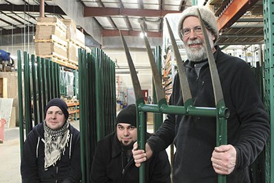 Bob Powell stands with one of his broadforks. Sitting are Meadow Creature machinist Paul Thibault and production manager Jared Middle Calf.