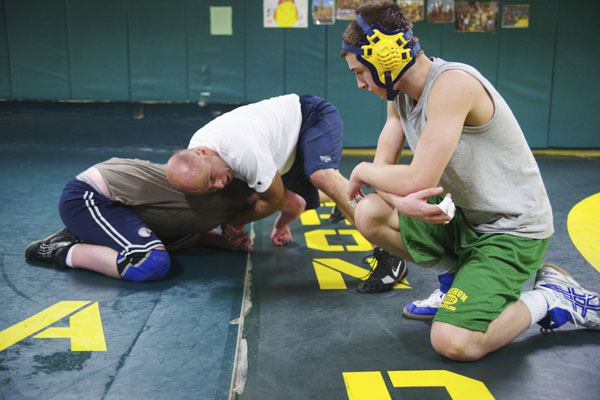 McMurray eighth-grader Palmer Burk watches as coach Corey McIntyre demonstrates a headlock on eighth-grader Franklin Easton. Many of the McMurray wrestlers took time from their Winter Break to practice.
