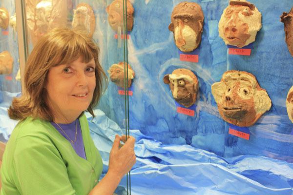 Pamela McMahan shows off a display of ceramic primate faces by Island kids. More of the works will be on display in the Vashon Bookshop hallway during the First Friday gallery cruise.