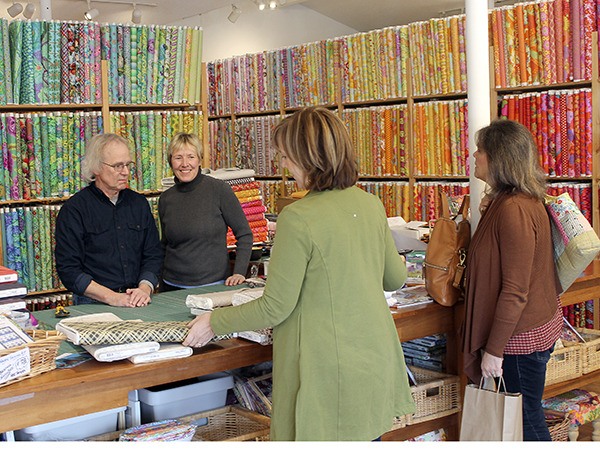 Paul Robinson and Anja Moritz help  customers purchasing fabric last Friday at Island Quilter. The customers