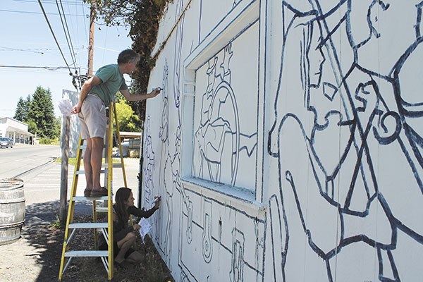 Bruce and Madeline Morser work on a mural on the side of the McFeeds building.
