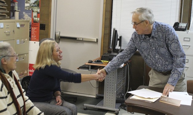 Elaine Ott shakes John Hopkins' hand after she accepts the park district board's offer to become the new director of the agency. Next to her is Hilary Emmer.