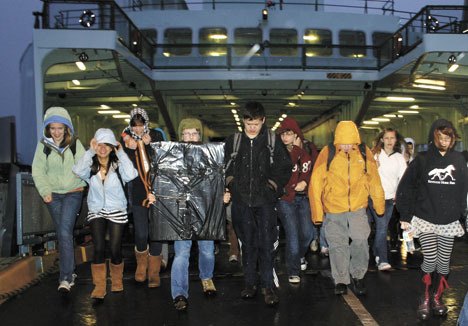 Students from West Seattle stream off the boat on a dark and rainy morning last week.