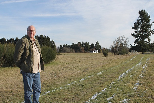 Land trust director Tom Dean stands at the Matsuda property the land trust plans to purchase. The 12 acres was once a strawberry farm and still holds a farmhouse and garages.