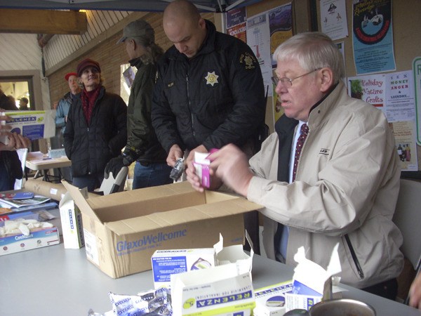 Pharmacist Dave Willingham sorts through medications at Operation Medicine Cabinet with King County Sheriff’s Deputy Mark Brown. Behind him Gretchen Burkholder of Vashon Youth & Family Services talks with Luke McQuillin as they help with the event.