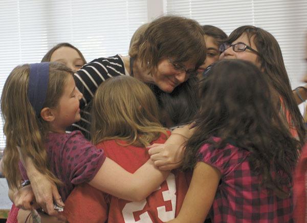 Carolyn Buehl is hugged by fifth graders at the end of class.