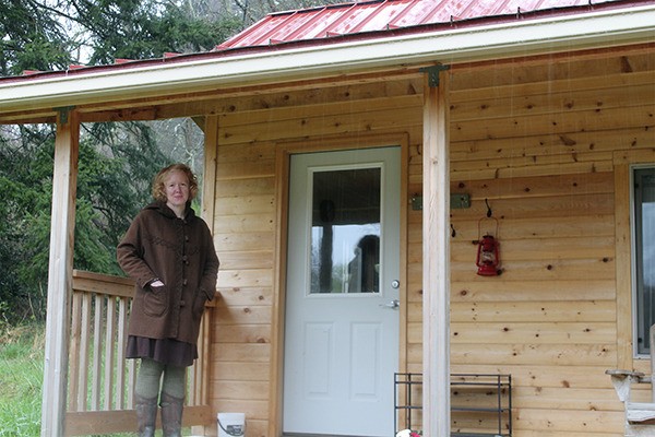 Juniper Rogneby stands outside her family’s 192-square-foot tiny house that is being used as a guest house.