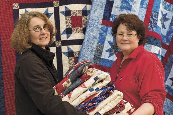 Su DeWalt and Sue Nebeker display some of the quilts that will soon be covering wounded troops in Afghanistan.