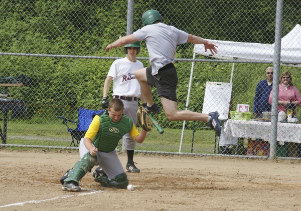 Micah Deibell leaps high to score a run as catcher Ryan Bernheisel scrambles to gather in the ball. Next batter Justin Calhoun watches the action in the Jim Martin Alumni Baseball  Game.
