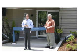 Bert Valdman and Jim English address a small crowd before cutting the ribbon at the reopening of Vashon’s PSE office.