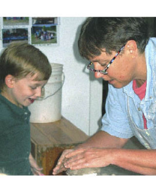 Potter Liz Lewis works with a young clay enthusiast.