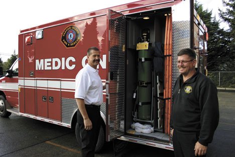 Assistant Chief George Brown and maintenance supervisor Brett Kranjcevich show off the new ambulance and its oxygen tank.