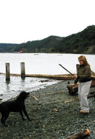 Susan Ross and her dog Snoop enjoy a game of fetch on Gold Beach. Glacier’s floating red crane looms in the distance.