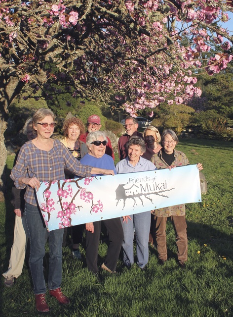 Anneli Fogt/Staff PhotoMembers of the Friends of Mukai board gather among the cherry blossoms at the Mukai property on Thursday with signs to celebrate their court victory. After years of legal battles