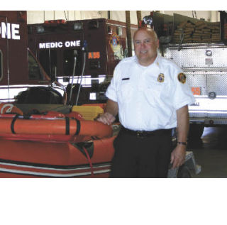 Hank Lipe stands next to the rubber boat Vashon Island Fire & Rescue uses for marine rescue. Lipe significantly increased marine capabilities at his former fire department.