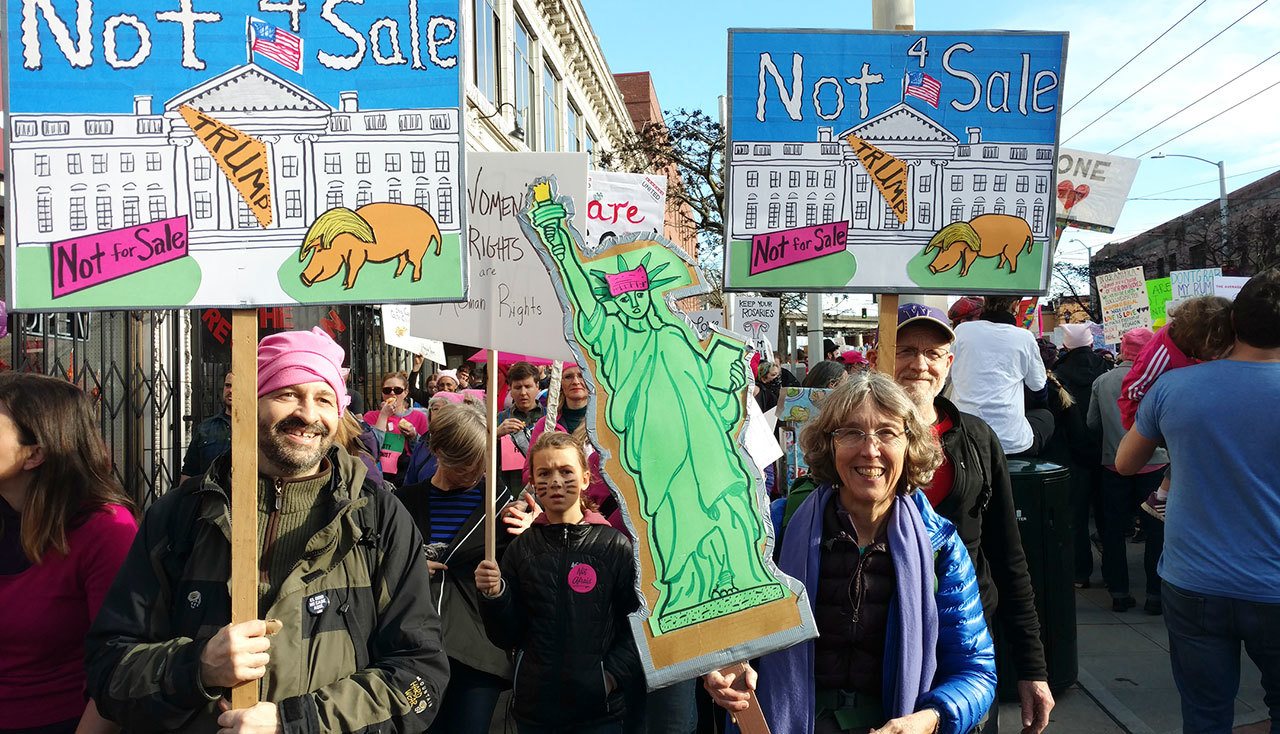 Islanders Denny Levin (left, in green), Marcie Rubardt (right, in blue) and Charlie Pietirick (behind, in UW baseball cap) march in the Seattle women’s march on Saturday. They were three of an estimated 175,000 that showed up to march against Trump by uniting for women, the LGBT community, immigration and the environment. (Susan Riemer/Staff Photo)