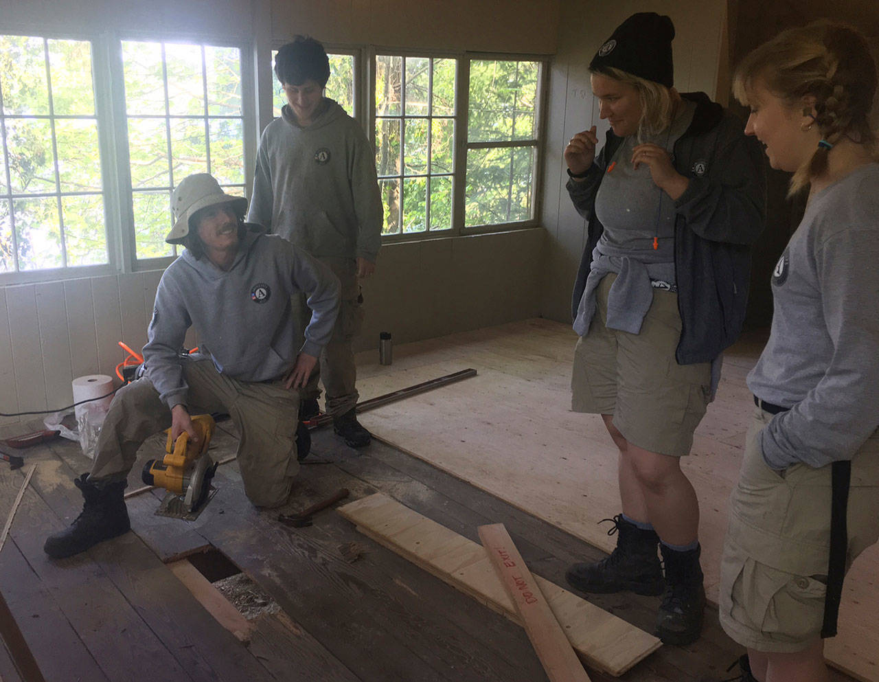 Three members of an 11-member Americorps team that have been working since March on a variety of improvement projects at Camp Sealth, replace the floor of a cabin on Tuesday morning. Pictured left to right: Nik Holder, John Bubeck, Kelsey Stoneberger and Emily Moore. (Anneli Fogt/Staff Photo)