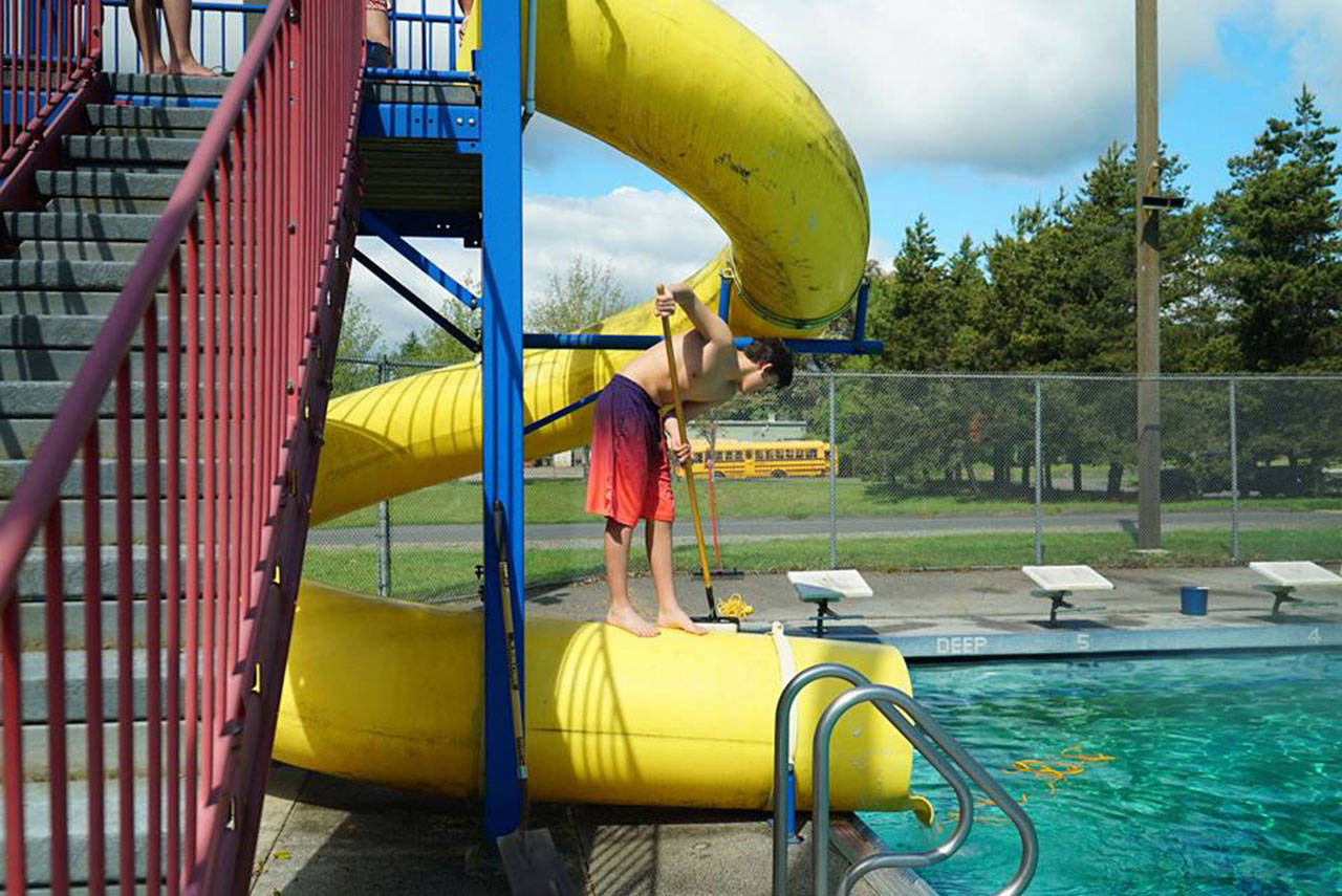 A member of the Vashon Seals swim team cleans the slide at the Vashon Pool ahead of this weekend’s opening. (Courtesy Photo)