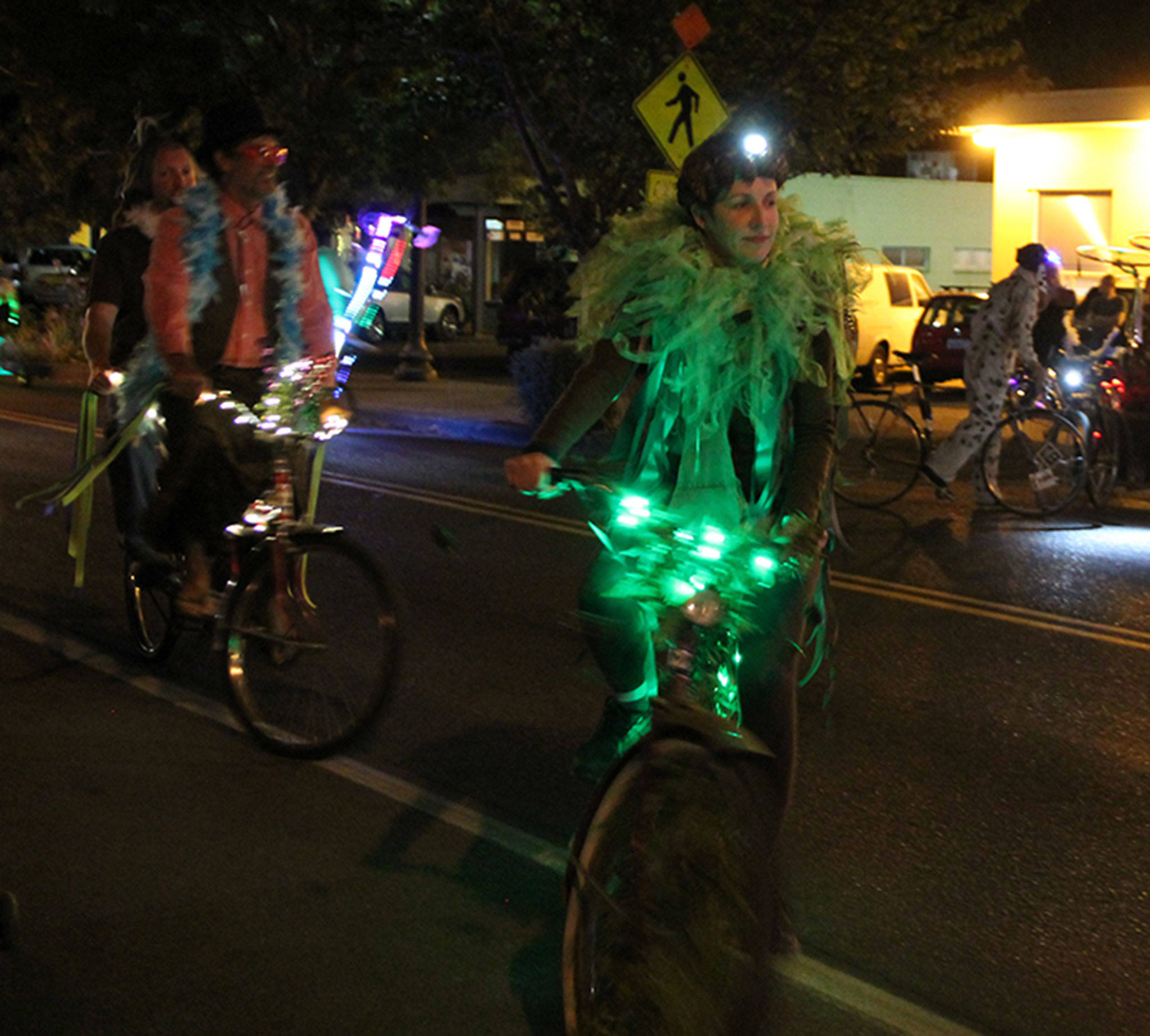 A woman rides a lit-up bike decked out in a green costume. (Susan Riemer/Staff Photo)