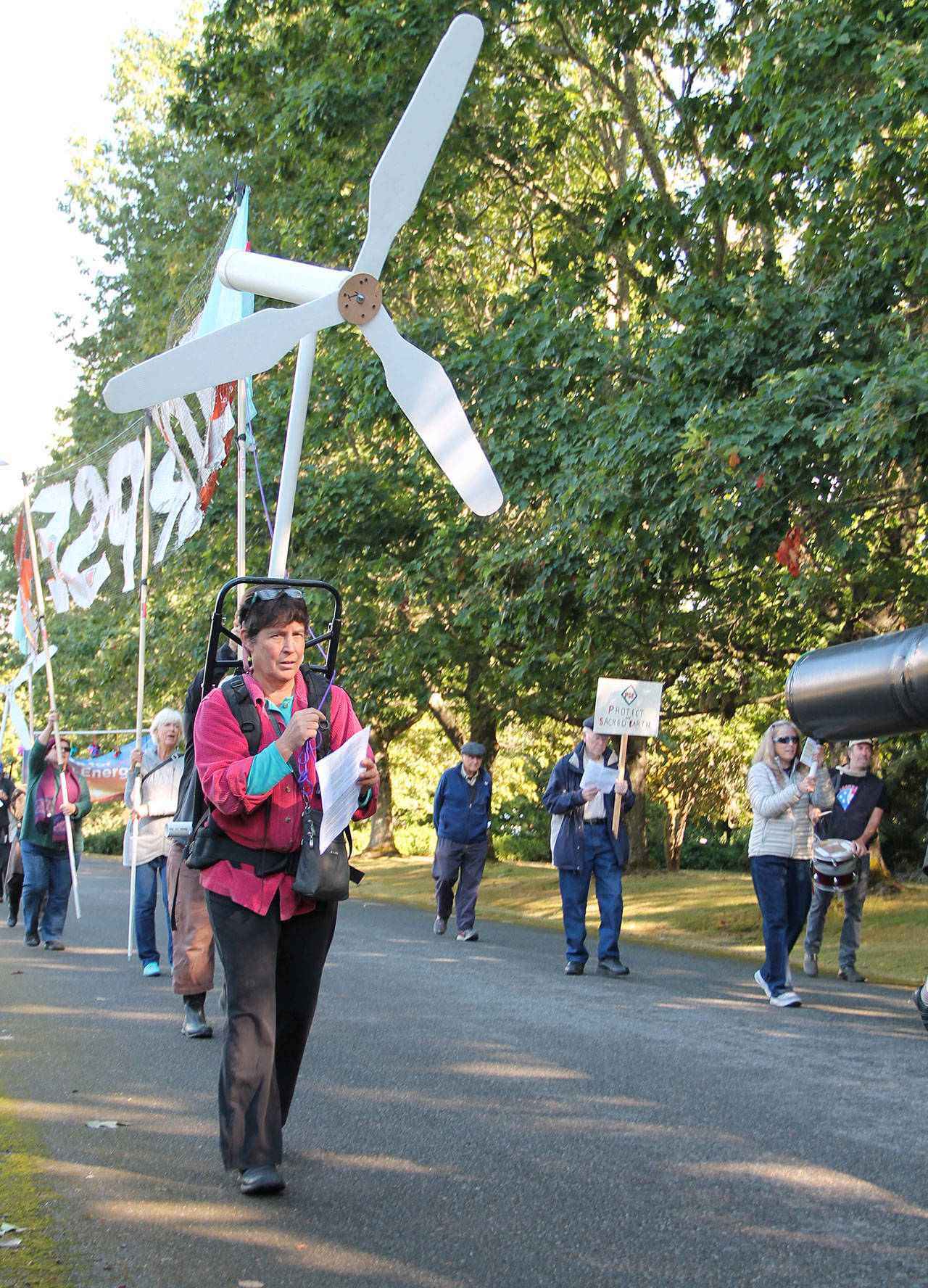 Islander Trish Howard wears a Backbone Campaign backpack featuring a wind turbine during the PSE Regional Day of Action demonstration on Vashon. (Anneli Fogt/Staff Photo)
