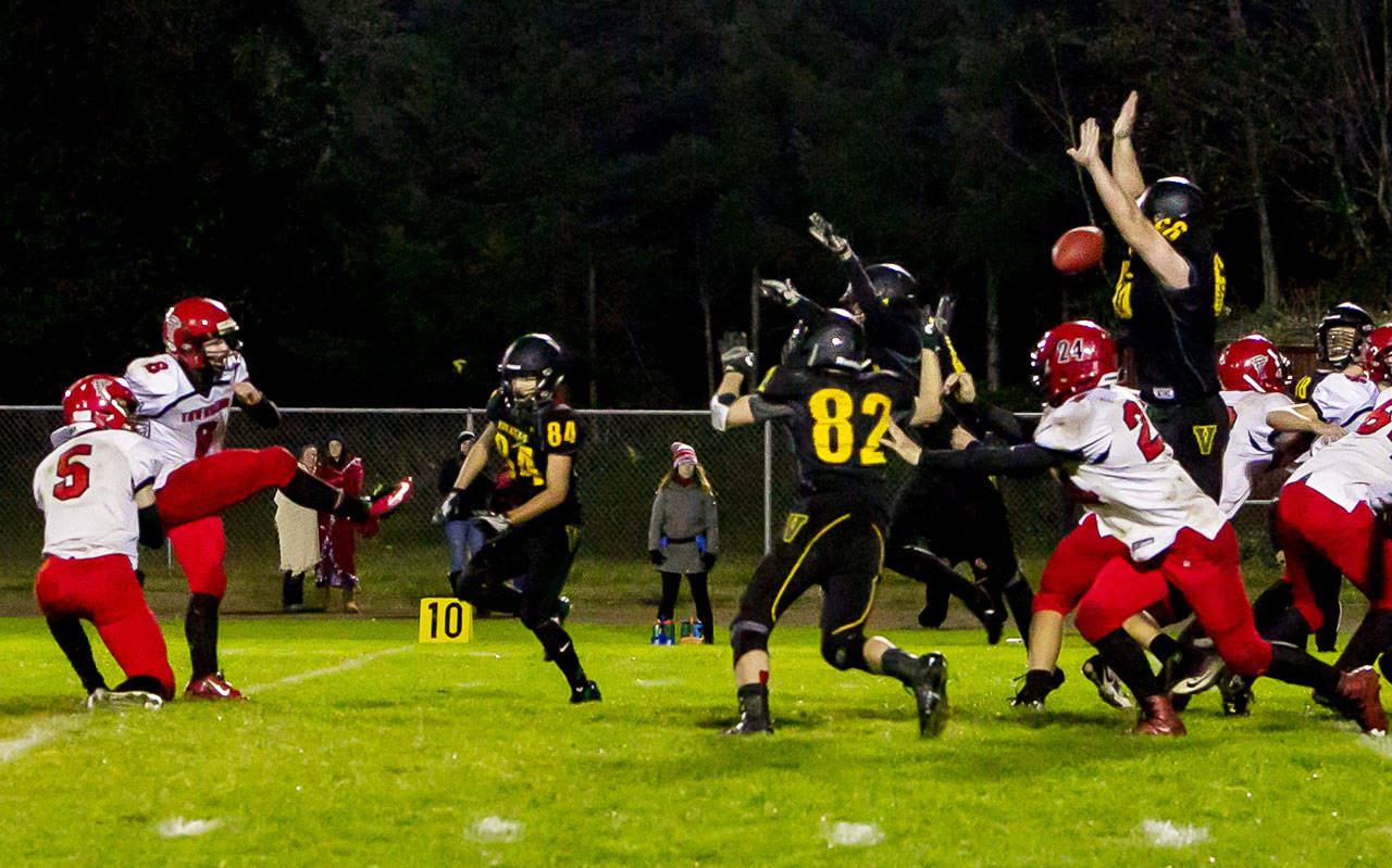 Vashon High School senior Cody Whitman (far right, #66) jumps up to block a point-after kick from Port Townsend’s Nico Winegar. Vashon’s Jonathan Quintans (#84), Steven Rice (#82) and Will Hennessey (behind Rice) assist. The Redhawks had just scored to tie with the Pirates 21-21 in the first overtime period and had they made the kick, they would have won the game. After a second overtime period, Vashon won 27-21. (John Sage/FinchHaven Photo)