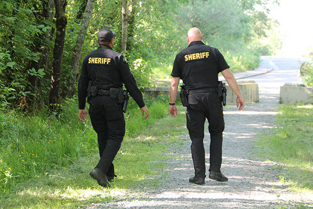 Paul Rowley/Staff Photo                                King County Sheriff’s Deputies Seth Moore and Glen Brannon in Island Center Forest.