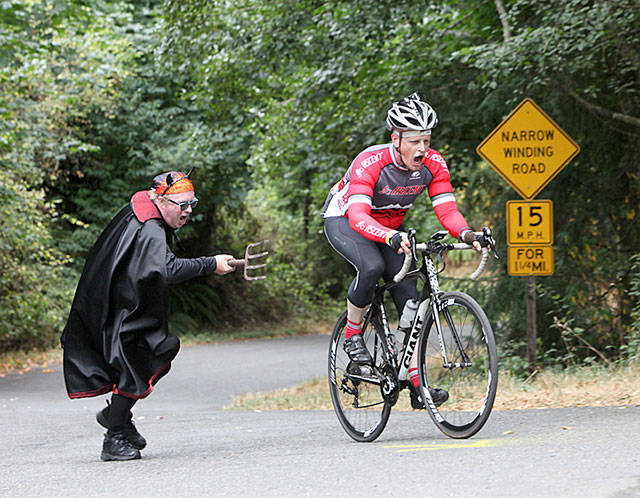 The Devil (Jim Marsh) prods — or inspires — a cyclist up challenging Burma Road in a previous P2P (David Weller Photos).
