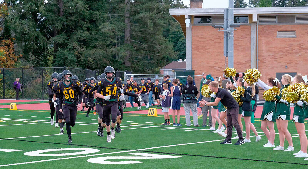 The Pirate football team runs onto the new field following the ribbon-cutting ceremony on Friday night. (Kent Phelan Photo)
