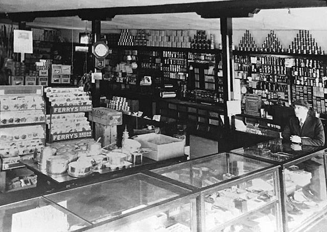 Coy Meredith sits at a counter inside the Burton Store likely in the 1920s. (Photo courtesy of the Vashon-Maury Island Heritage Museum)