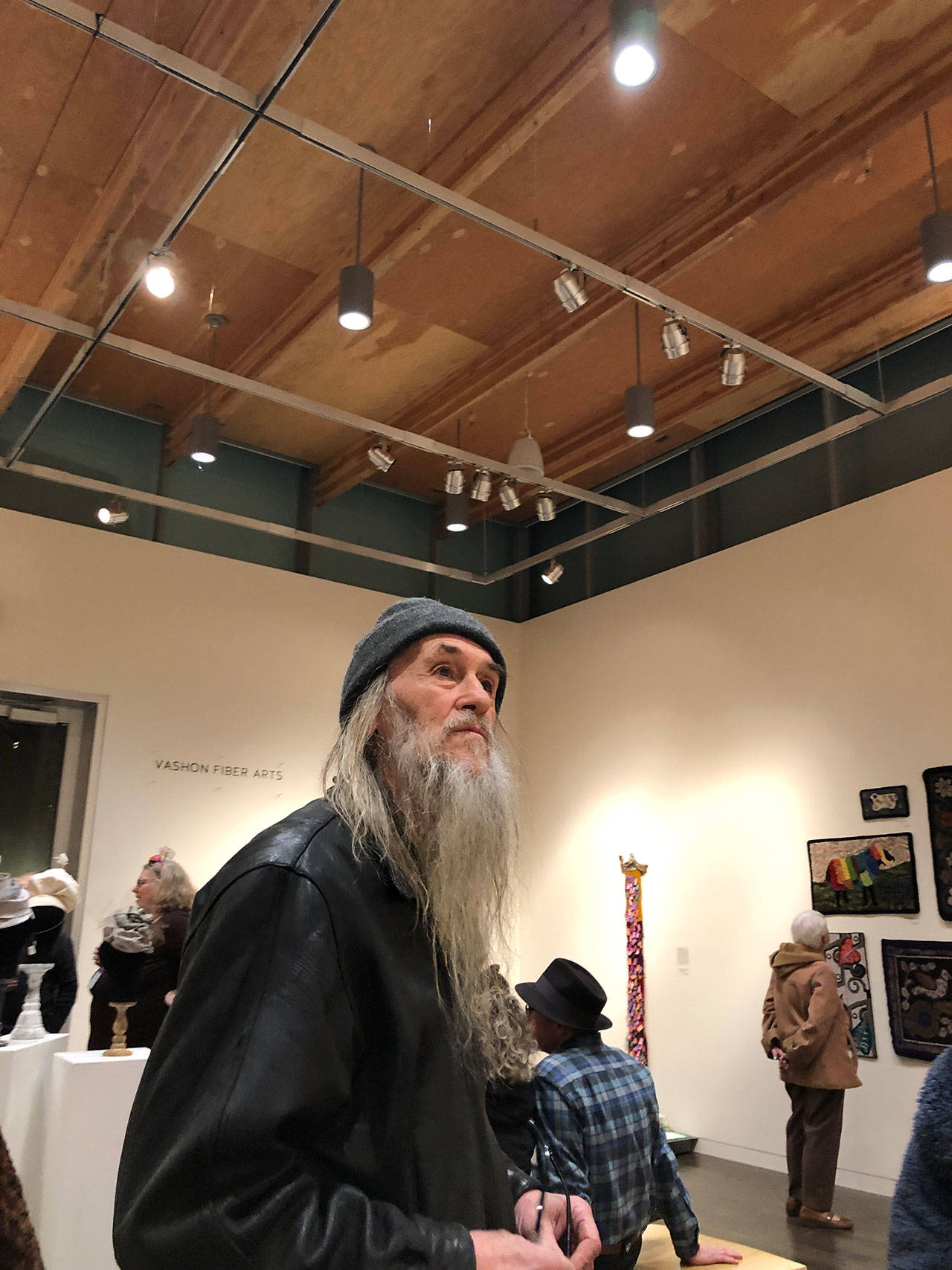 Ron Hook, a stalwart of Vashon’s art and music scene, checks out a recent fiber arts exhibition at VCA’s Koch Gallery (Tom Hughes Photo).