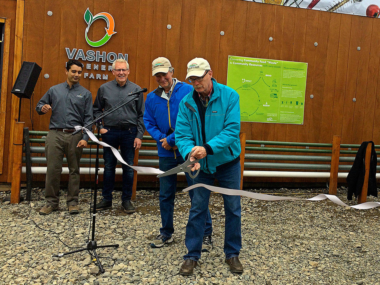 Gib Dammann, president of Zero Waste Vashon, cuts the ribbon on a new anaerobic digester unveiled Tuesday at the Island Spring Organics tofu factory. From left, those gathered include Srirup Kumar and Jan Allen of Impact Bioenergy and Steve Bergman, also of Zero Waste Vashon (Susan McCabe Photo).