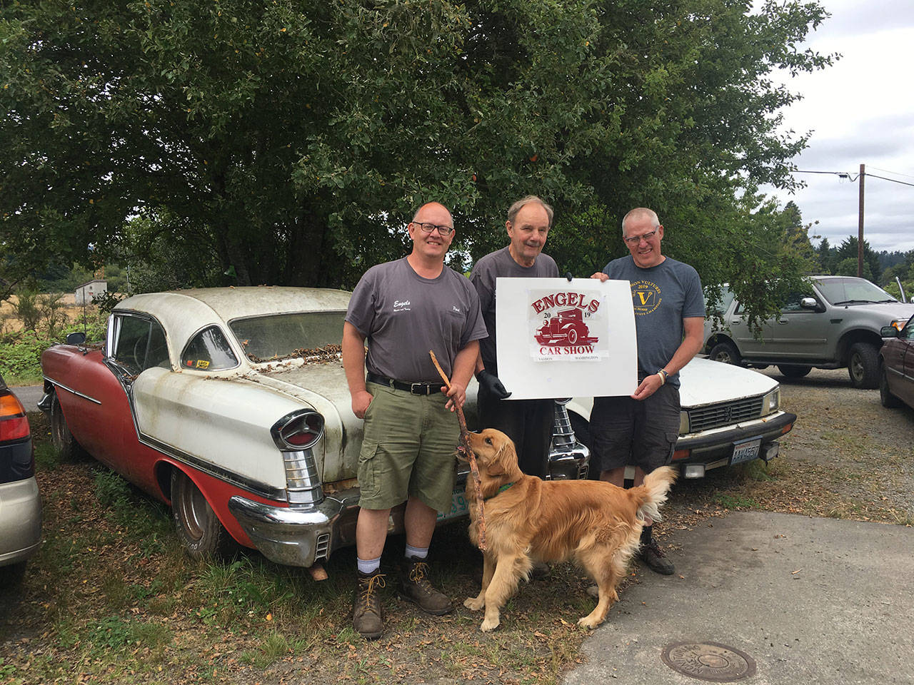 Paul Engels, Lou Engels, designer and car collector Chris Barnes and Archie, the Engels’ shop dog, get ready for the annual car show at Engels Repair and Towing (Elizabeth Shepherd Photo).