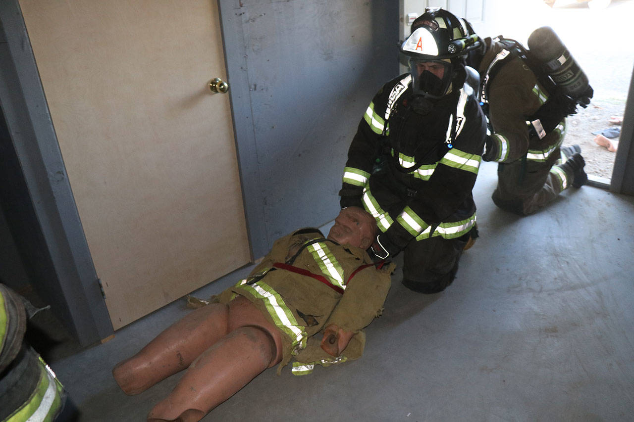 Members of the current firefighting academy pull a “victim” to safety from the new search and rescue prop (Cari Coll Photo).