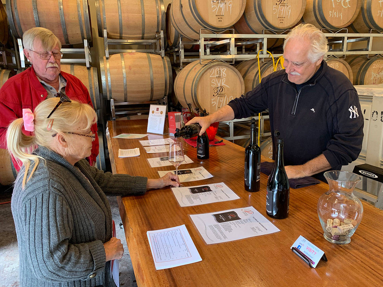 George Kirkish, owner and founder of Palouse Winery on Vashon-Maury Island, pours a glass of wine for Lori Coots on Saturday, Sept. 21, during tasting room hours (Kevin Opsahl/staff photo).