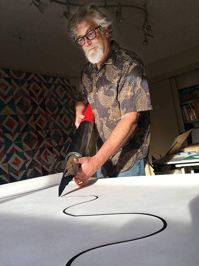 Jim Woodring uses his giant pen tool to draw a picture at his home (Andy James Photo).
