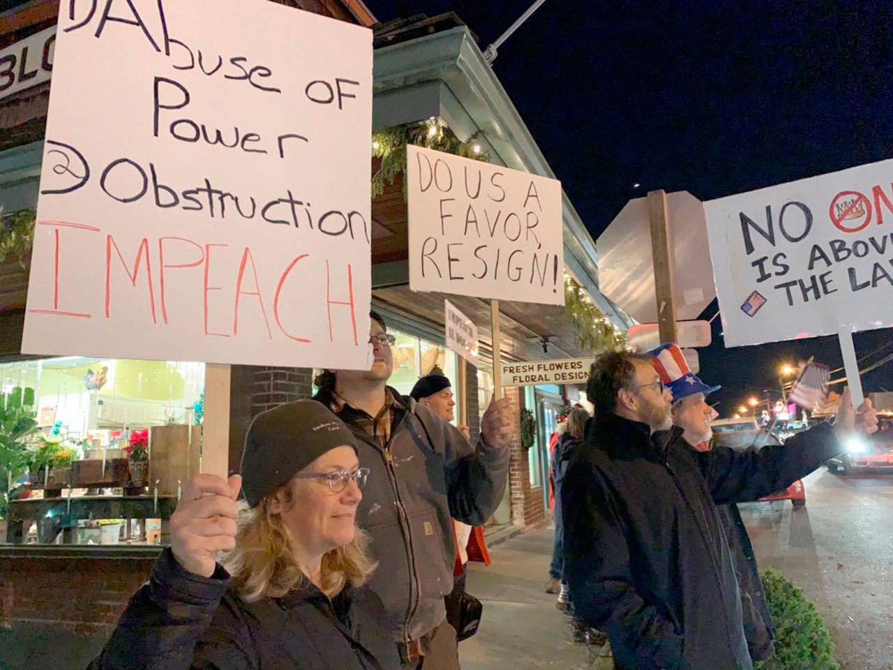 Zoe Rothchild, in the foreground, holds a sign stating the articles of impeachment against President Donald Trump as others demonstrate during a “Nobody’s Above the Law” rally on Tuesday, Dec. 17 at Vashon Highway and Bank Road. The demonstration was held one day before the House of Representatives was expected to impeach the president (Kevin Opsahl/Staff Photo).