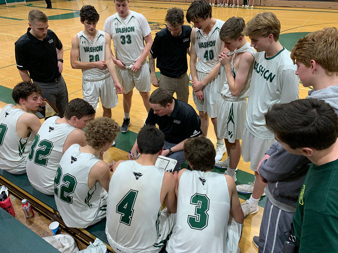 Coach Andy Sears, assistant coaches and the Vashon High School boys basketball team huddle during a game. (Doug Langworthy / Photo)