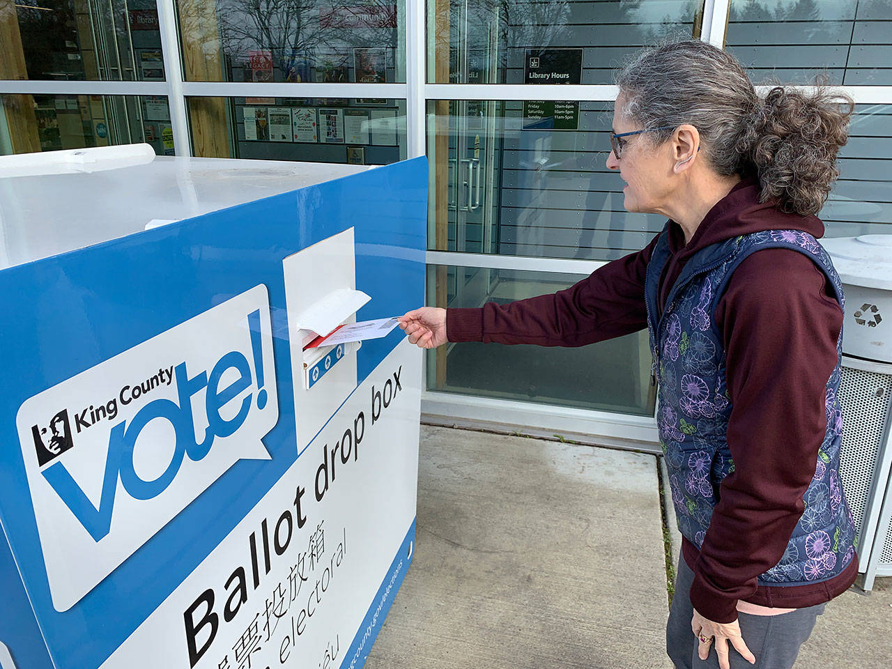 Island resident Pati Russell-Lamboau drops off her ballot at the King County Elections voter drop box at the library on Friday, Feb. 28. (Kevin Opsahl/Staff Photo)