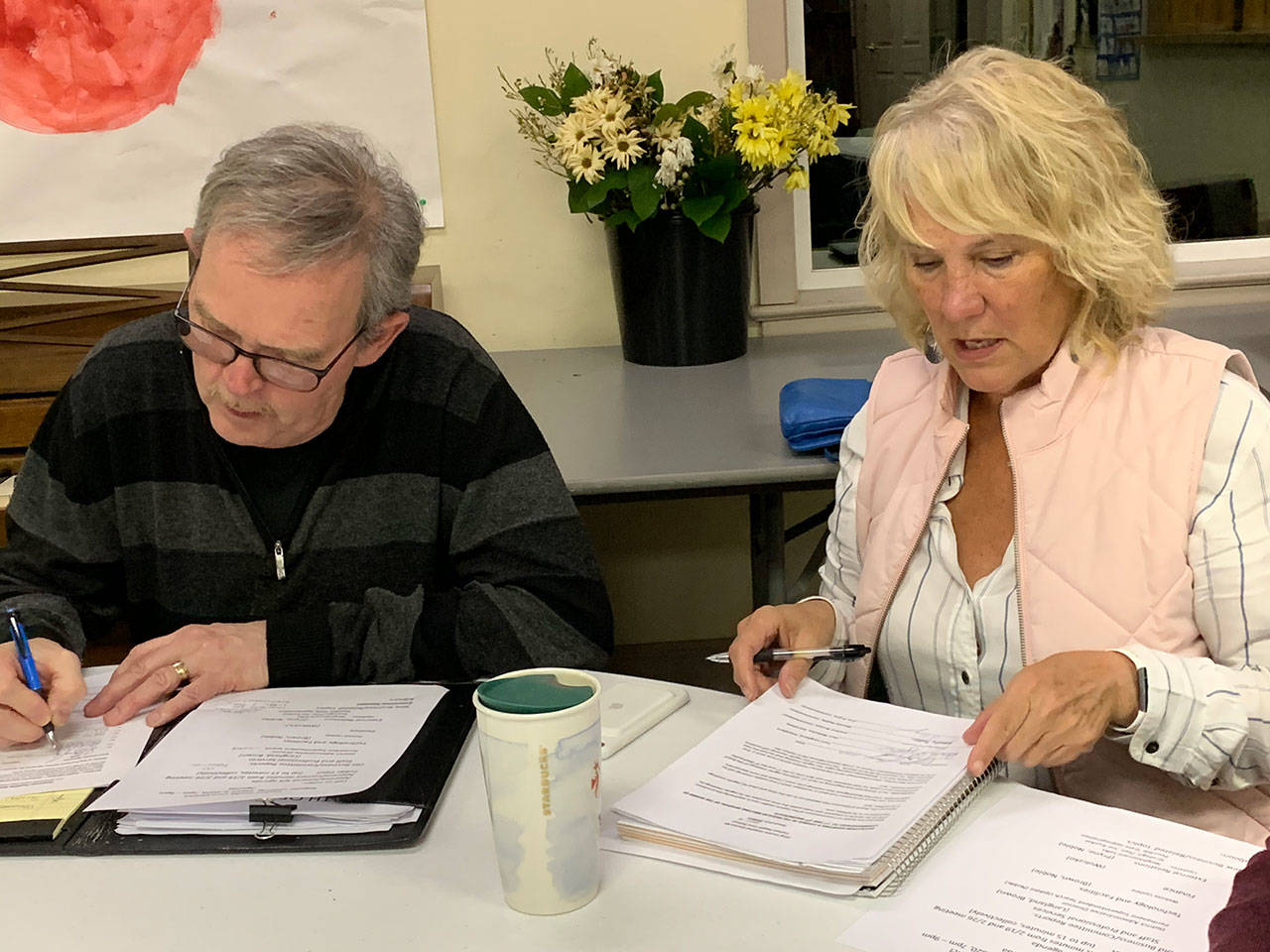 Tom Langland, president of the board of commissioners for the Vashon Health Care District, and fellow commissioner LeeAnn Brown, fill out paperwork after the district’s meeting on March 4, at the presbyterian church. (Kevin Opsahl/Staff Photo)