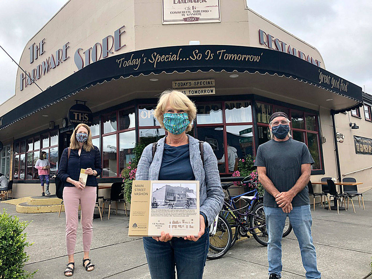 From left: Elsa Croonquist, Sue Hardy and Brian Brenno stand in front of the historic building now housing The Hardware Store Restaurant  a stop on the Main Street Vashon: A Walk through History, a new, self-guided walking tour presented by the Vashon Heritage Museum (Tom Hughes Photo).
