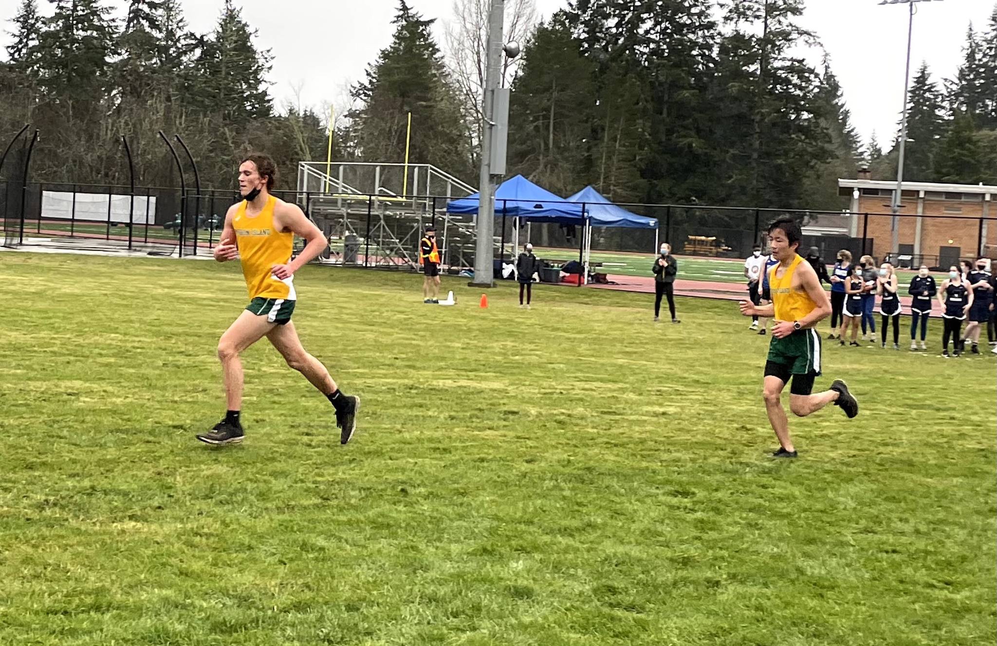 Ben Larson (left) and Levi Blasingam (right) running through the muddy grass on their second loop of the cross-country course, which was modified to allow for social distancing.