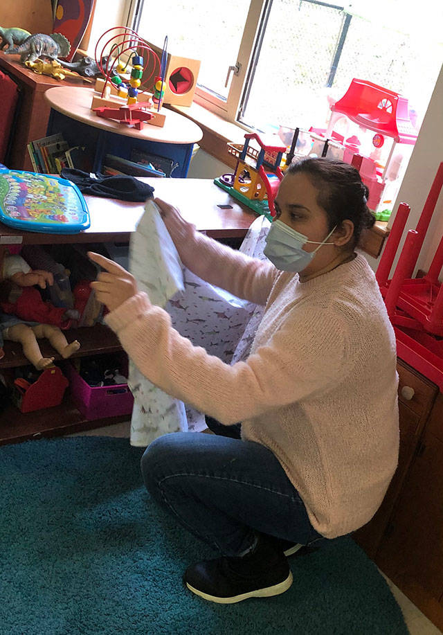 Teacher Laura Favela helps ECEAP pre-schoolers tidy up before they can go outside to play (Susan McCabe Photo).